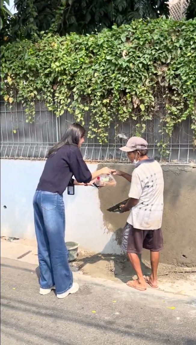 Relawan Cinta Foundation menyerahkan paket makanan kepada seorang pekerja di tepi jalan