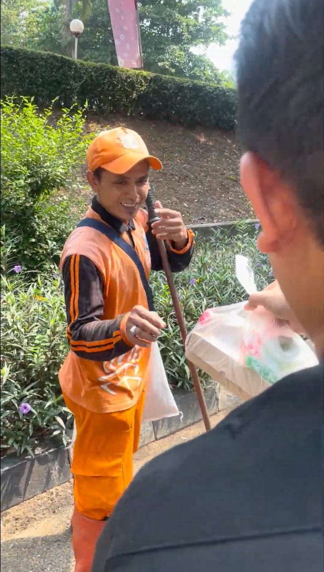 Seorang petugas kebersihan menerima paket makanan Jumat Berkah